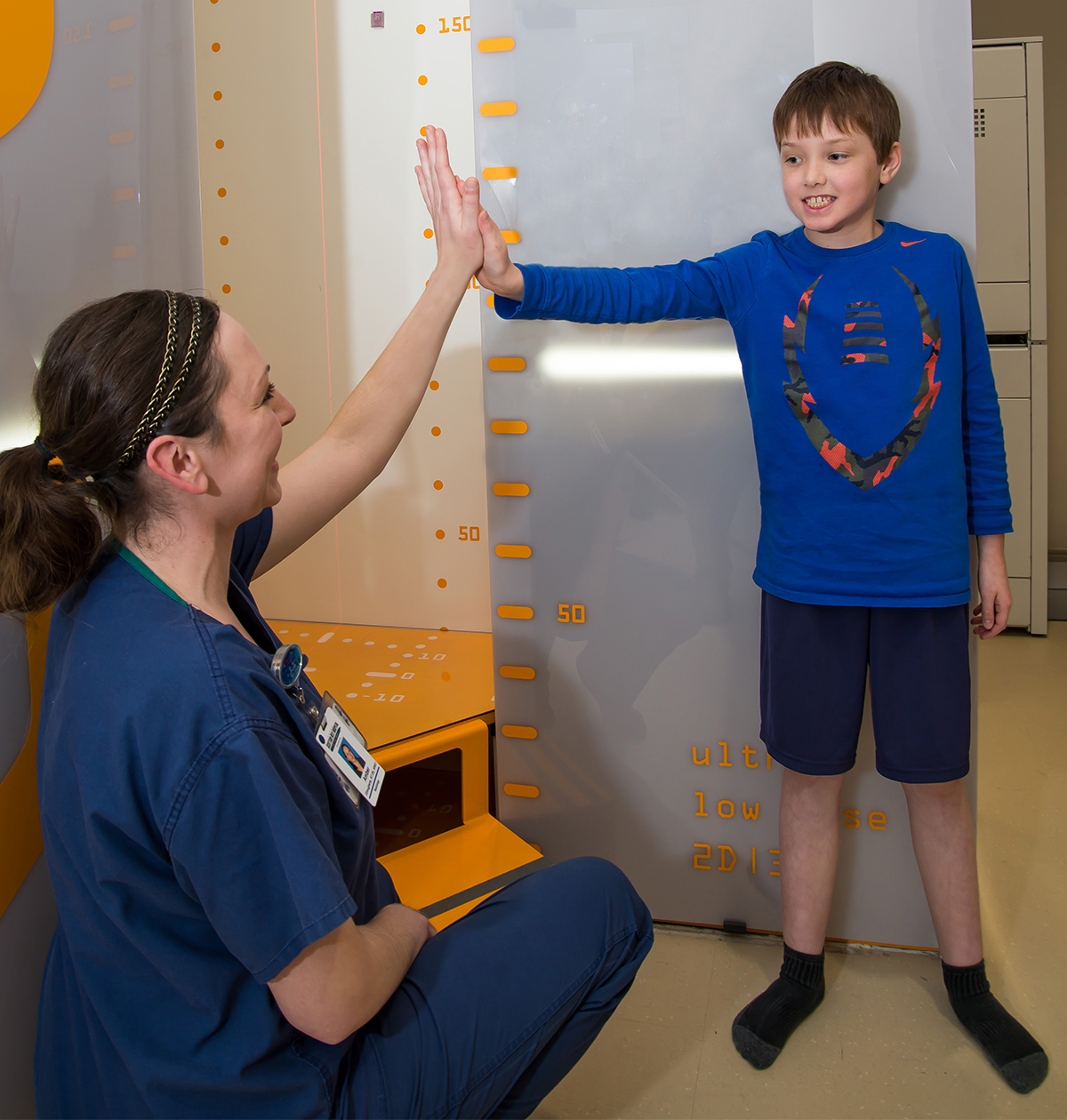 Radiology nurse high-fiving patient after X-rays were taken at Texas Scottish Rite Hospital for Children